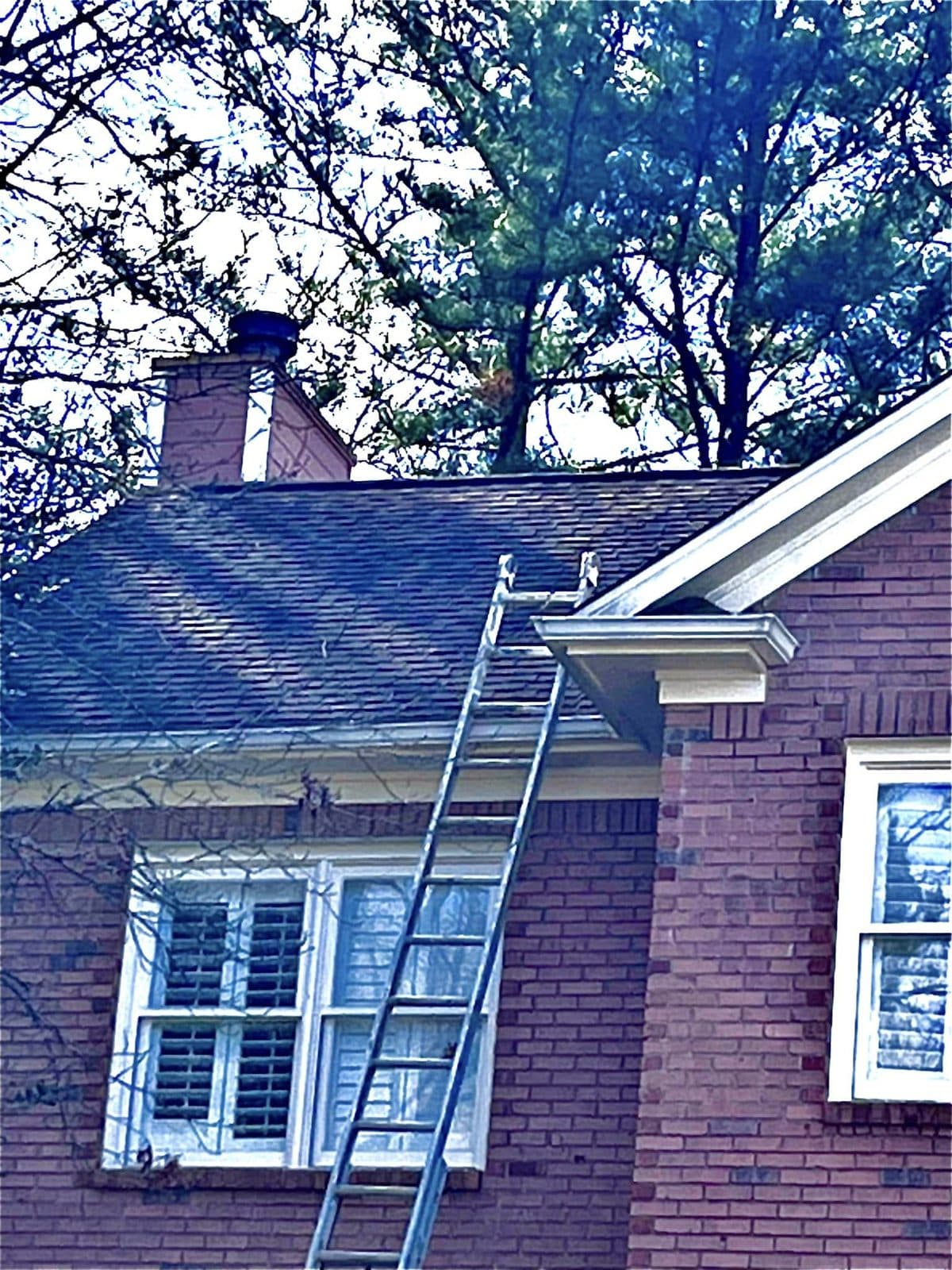 Ladder set against a red brick two story home during a roof wash, Birmingham metro