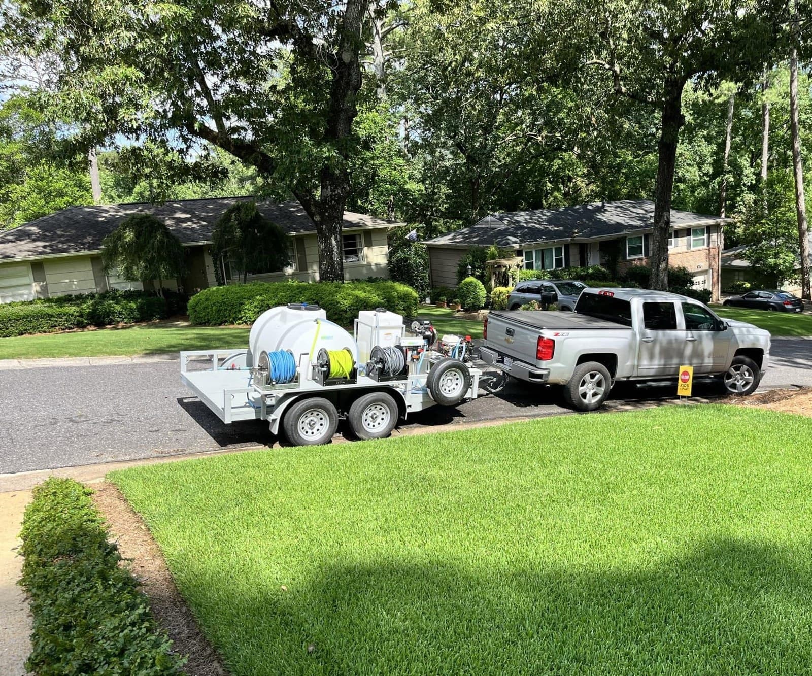 Pressure washing trailer with tanks hitched to the truck at the curb, Birmingham metro