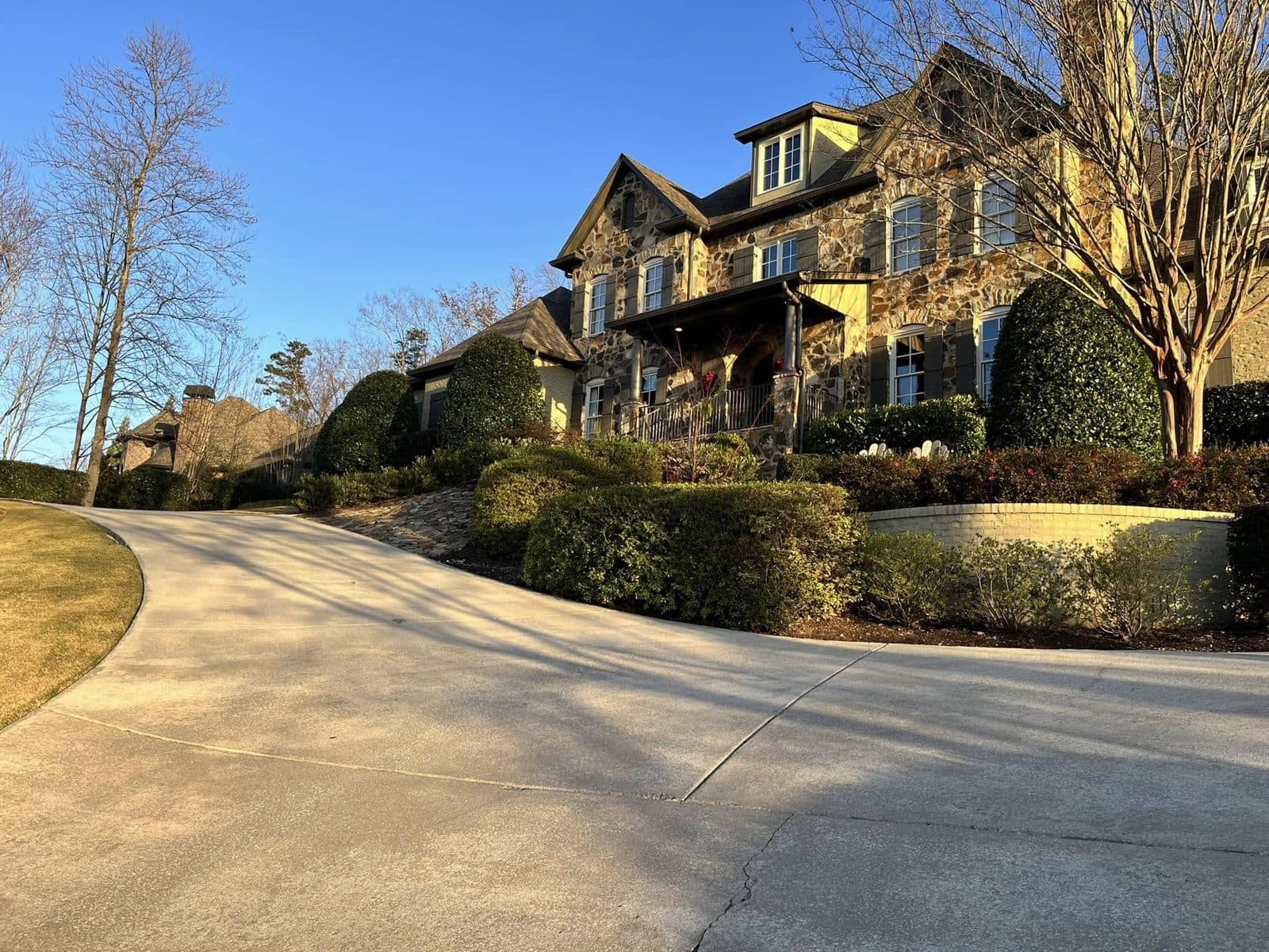 Stone front home and its long concrete drive after cleaning, late afternoon light, Birmingham metro